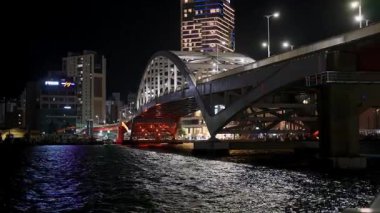 BUSAN, GÜNEY KOREA - 10 EKİM 2025 - Parıldayan bir nehir boyunca uzanan modern bir köprü ile Busan şehri