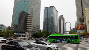 SEOUL, Güney Kore - 11 Ekim 2025 Modern binalar, sürüş arabaları ve hareket eden yeşil bir otobüsle Global Metropolis Caddesi
