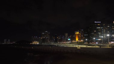 BUSAN, Güney Kore - 9 Ekim 2025 - Şehir ışıkları Haeundae Sahili 'ne yansıyor.