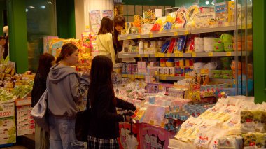 SEOUL, Güney Kore - 11 Ekim 2025 - Kadınlar parlak ışıklandırılmış Asya pazarında eşyalar ve taze ürünlere bakıyorlar