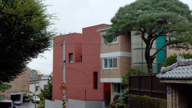 SEOUL, Güney Kore - 11 Ekim 2025 - Arabalarla dolu dar bir cadde ve bulutlu bir gökyüzünün altında elektrik direği olan yerleşim yerleri