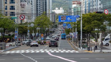 BUSAN, Güney Kore - 9 EKİM 2025 Busan, Güney Kore 'de uzun binalar ve yol tabelalarıyla kalabalık bir şehir caddesinde hareket eden araçlar