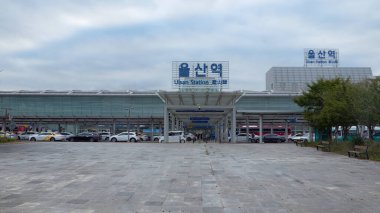 ULSAN, Güney Kore - 10 Ekim 2025 - Önünde arabalar ve otobüsler olan Ulsan İstasyonu binası, modern ulaşım ve seyahati temsil ediyor