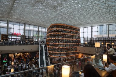 SEOUL, Güney Kore - 11 Ekim 2025 Bir alışveriş merkezi içinde modern bir çok katlı kütüphaneye göz atan insanlar