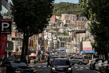 BUSAN, Güney Kore - 9 Ekim 2025 - Busan 'da yoğun trafik ve yaya faaliyetleri olan şehir merkezi ve tepe binaları