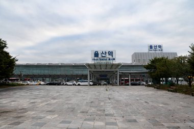 ULSAN, Güney Kore - 10 Ekim 2025 Ulsan İstasyonu dış binası giriş, plaza ve park halindeki arabaları bulutlu bir gökyüzünün altında gösteriyor