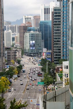 SEOUL, Güney Kore - 11 Ekim 2025 - Seul 'deki çok şeritli bir yolda hareket eden gökdelenleri ve arabaları gösteren yüksek açı