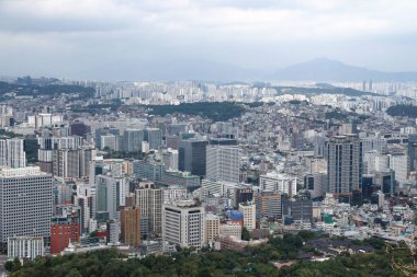 SEOUL, Güney Kore - 11 Ekim 2025 - Uzak dağları olan bulutlu gökyüzü altında sayısız binanın bulunduğu Seul kentsel manzarası