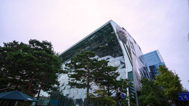 SEOUL, Güney Kore - 11 Ekim 2025 - Seul Belediye Binası eşsiz cam cephe ve parlak bir gökyüzü altında yeşil ağaçlar