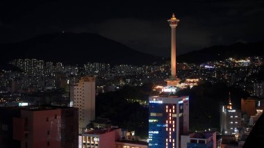 BUSAN, Güney Kore - 10 Ekim 2025 Busan şehir ışıkları kentsel ufuk çizgisini aydınlatıyor ve geceleyin Busan Kulesi 'ni simgeliyor