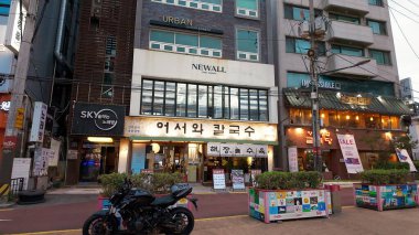 SEOUL, Güney Kore - 11 Ekim 2025 - Hongdae 'deki yoğun Kore restoranları ve işletmeleri önünde motosikletli sokak sahnesi