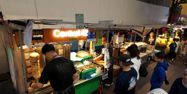 SEOUL, Güney Kore - 11 Ekim 2025 Myeongdong, Seul 'deki canlı bir gece marketinde kebap hazırlayan bir satıcı