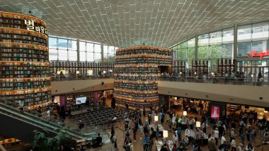 SEOUL, GÜNEY KOREA - 11 Ekim 2025 - Yüksek kitap rafları ve kitap keşfeden birçok kişi ile kamu kütüphanesinin içini aç