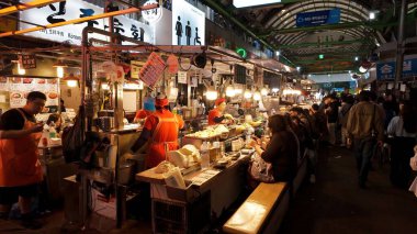 SEOUL, Güney Kore - 11 Ekim 2025 Seul 'deki yoğun bir gece pazarında satıcılar tarafından hazırlanan sokak yemeklerini beğenen insanlar