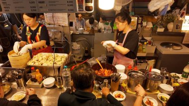 SEOUL, Güney Kore - 11 Ekim 2025 - Müşteriler için geleneksel Kore yemekleri ve hamur tatlısı hazırlayan meşgul kadınlar