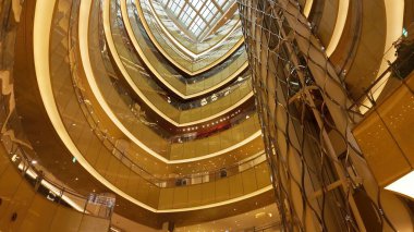 SEOUL, Güney Kore - 11 Ekim 2025 - Güney Kore 'de eğri büğrü altın mimarisi ve cam parmaklıkları olan modern alışveriş merkezi avlusu