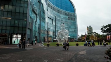 SEOUL, Güney Kore - 11 Ekim 2025 - İnsanlar Seul, Güney Kore 'de büyük bir heykel ile modern Lotte AVM binasının önünde yürüyorlar