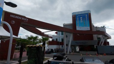 BUSAN, Güney Kore - 10 EKİM 2025 - Bulutlu bir günde Haeundae Sahili 'ne turist bilgi merkeziyle giriş işareti