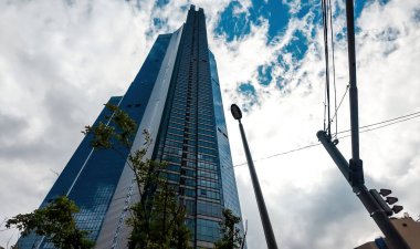 BUSAN, Güney Kore - 10 Ekim 2025 Busan, Güney Kore 'de bulutlu bir gökyüzüne uzanan cam cepheli modern gökdelen