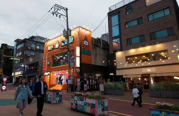 SEOUL, Güney Kore - 11 Ekim 2025 Hongdae, Seul, Güney Kore 'de aydınlık binaları olan kalabalık bir caddede yürüyen insanlar