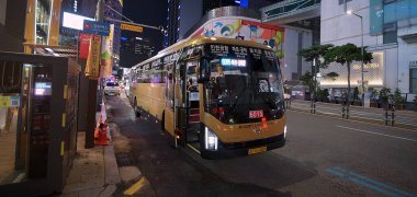 SEOUL, GÜNEY KORE - 11 Ekimde. 2025 - Sarı havaalanı otobüsü Seul 'ün kalabalık bir caddesine park etmiş, yolcuları topluyordu.