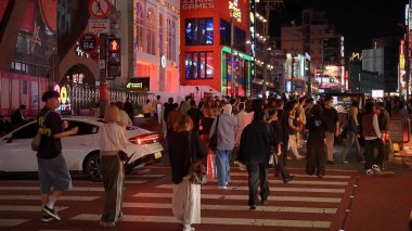SEOUL, GÜNEY KORE - 11 Ekimde. 2025 - Güney Kore 'nin kalabalık Hongdae bölgesinde geceleyin yaya geçidinde yürüyen insanlar