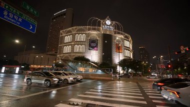 SEOUL, GÜNEY KORE - 11 Ekimde. 2025 - Seul, Güney Kore 'de gece sokak trafiği ve ıslak yollarla aydınlatılmış Lotte Mağaza Binası