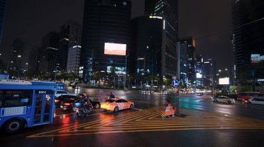 SEOUL, GÜNEY KORE - 11 Ekimde. 2025 - Yağmurdan sonra şehir ışıklarını yansıtan arabalar, otobüs ve binalarla ıslak kesişme
