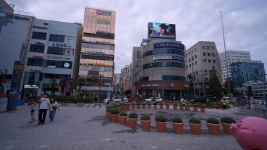 BUSAN, GÜNEY KORE 10 EKİM. 2025 - Busan 'da ekicilerle süslenmiş bir sokak kavşağının yanından geçen yayalar