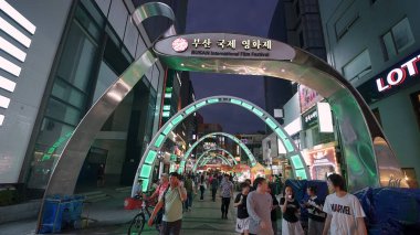 BUSAN, GÜNEY KORE 10 EKİM. 2025 - İnsanlar Busan, Güney Kore 'deki BIFF Meydanı' nda parlak kemerlerin altında yürüyorlar