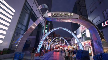 BUSAN, GÜNEY KORE 10 EKİM. 2025 - BIFF Meydanı kemerli ve neon ışıkları insanları film festivaline davet ediyor