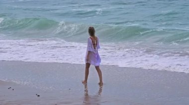 Kumsalda yürüyen bir insanın huzur dolu bir sahnesi. Yakınındaki nazik dalgalarla. Huzur ve sükuneti simgeliyor.