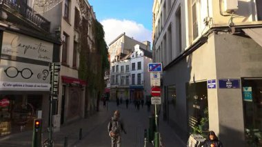 BRÜKSEL, BELGIUM - 26 Kasım 2025 - Geleneksel mimari ve dükkanlarla dolu dar bir Avrupa caddesinde yürüyen insanlar