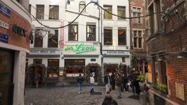 BRÜKSEL, BELGIUM - 26 Kasım 2025 - Brüksel, Belçika 'da bir kaldırım taşı caddesinde yürüyen insanlar, tarihi restoranların yanından geçiyor
