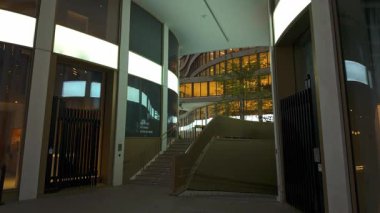 BRÜKSEL, BELGIUM - 26 Kasım 2025 - Eğri binalar ve alacakaranlıkta parlayan pencerelerle modern mimari kompleksi