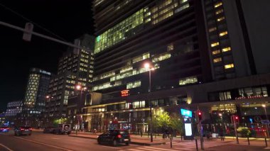 BRÜKSEL, BELGIUM - 26 Kasım 2025 - Brüksel şehir caddesi modern binaları, sokak lambalarını ve geceleri geçen arabaları gösteriyor