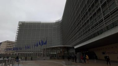 BRÜKSEL, BELGIUM - 26 Kasım 2025 - Berlaymont gökyüzü bulutlu, Avrupa bayraklarını ve dışarıda yürüyen insanları gösteren