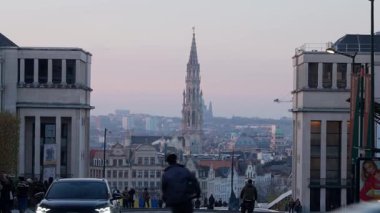 BRÜKSEL, BELGIUM - 26 Kasım 2025 - Brüksel gökyüzü alacakaranlıkta Belediye Binası kulesi görünür, insanlar Mont des Arts 'ta yürüyor ve bisiklet sürüyor