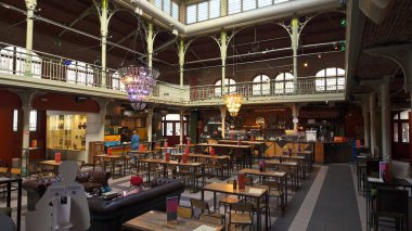 BRÜKSEL, BELGIUM - 26 Kasım 2025 - Barları, restoranları, masaları ve avizeleri olan büyük bir sanayi binasının içi