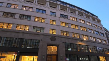 BRÜKSEL, BELGIUM - 26 Kasım 2025 - Brüksel şehir merkezindeki ofis binasında mavi saatte aydınlatılmış pencereler