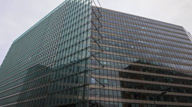 BRÜKSEL, BELGIUM - 26 Kasım 2025 - Cam ve beton cepheli modern ofis binası bulutlu bir günde kentsel mimariyi yansıtır