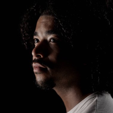 Siyah arka planda kıvırcık saçlı, yakışıklı bir Afro-Amerikan 'ın stüdyo portresi. Bu görüntü moda güzelliği ve editör projeleri için uygundur..