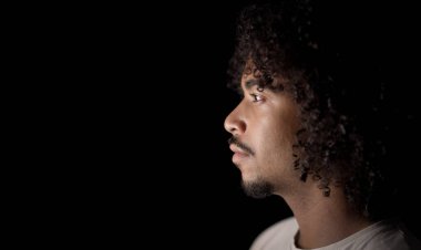 Siyah arka planda kıvırcık saçlı bir adamın stüdyo portresi. Bu görüntü güzellik ve moda reklam kampanyaları ve yazı işleri için uygundur..