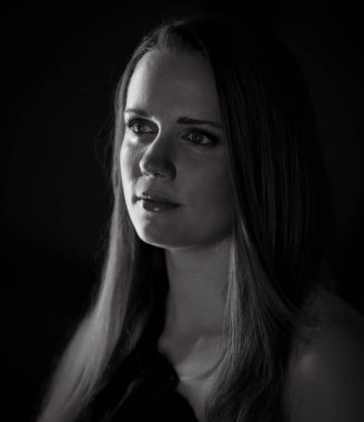 Tek renkli stüdyo portresi. Uzun saçlı güzel bir genç kadın. Bu görüntü, dramatik ışıklandırma ve karanlık bir arkaplan ile moda güzelliği ve sanat projeleri için uygundur..