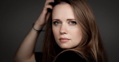 Stüdyo portresi, uzun kahverengi saçlı ve koyu renk arka planda poz veren yeşil gözlü güzel bir kadın. Bu görüntü moda güzelliği ve reklam projeleri için uygundur..