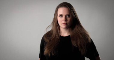 Gri arka planda uzun saçlı güzel esmer bir kadının stüdyo portresi. Bu görüntü moda güzelliği ve kozmetik projeleri için uygundur..