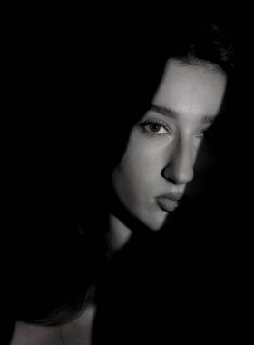 Dramatik ışıklandırması olan genç bir kadının tek renkli stüdyo portresi. Bu görüntü moda güzelliği ve editör projeleri için uygundur..