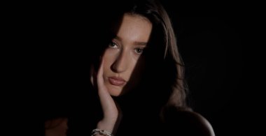 Güzel bir genç kadının stüdyo portresi. Elini çarpıcı bir şekilde aydınlatıyor. Karanlık bir arkaplana hafifçe dokunuyor. Bu görüntü moda güzelliği ve sağlık kavramları için uygundur..