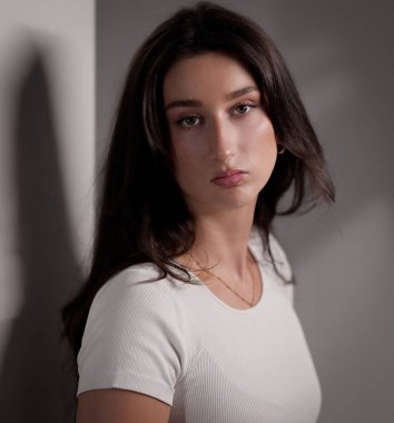 Beyaz bluz ve altın takılar takan güzel esmer bir kadının stüdyo portresi. Bu görüntü moda güzelliği ve yaşam tarzı projeleri için uygundur..