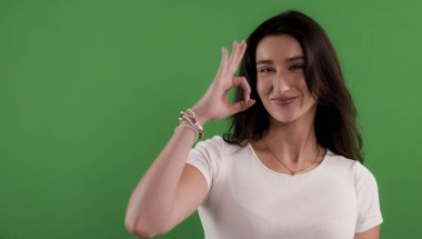 Yeşil arka planda esmer bir kadının el hareketi çekimleri. Bu görüntü moda güzelliği, yaşam tarzı içeriği ve ürün tanıtımları ve reklamları için uygundur..